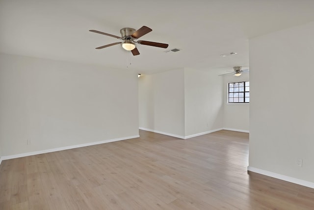 spare room with visible vents, ceiling fan, light wood finished floors, and baseboards