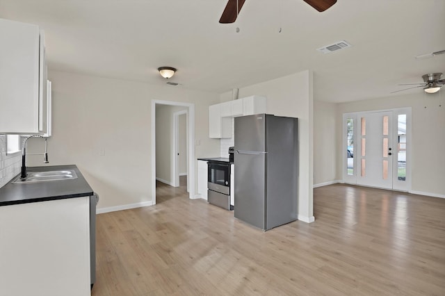 kitchen with black / electric stove, freestanding refrigerator, a ceiling fan, dark countertops, and a sink