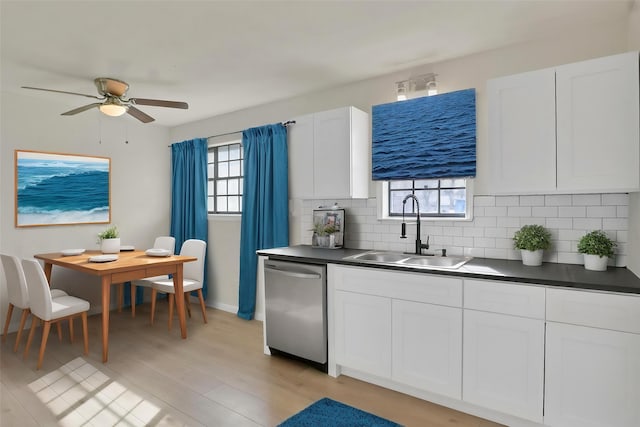kitchen with dishwasher, a sink, backsplash, and dark countertops