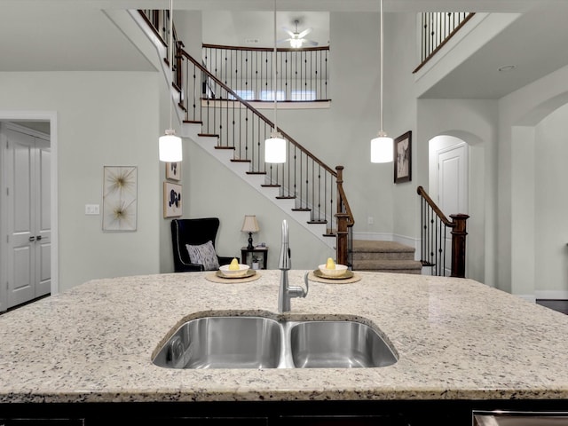 kitchen with hanging light fixtures, an island with sink, and light stone countertops