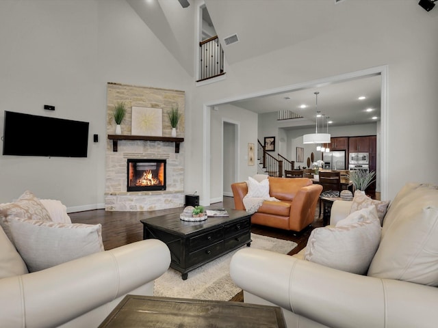 living room with hardwood / wood-style flooring, a stone fireplace, and high vaulted ceiling