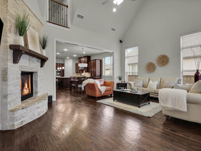 living room featuring ceiling fan, a fireplace, dark hardwood / wood-style floors, and high vaulted ceiling