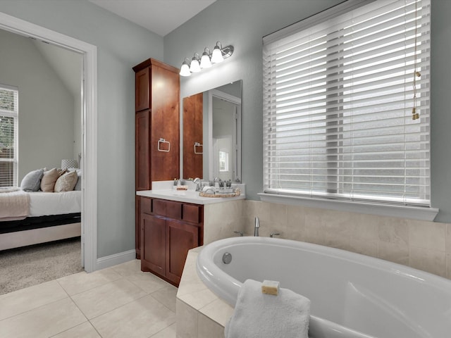 bathroom with tile patterned flooring, vanity, and tiled bath