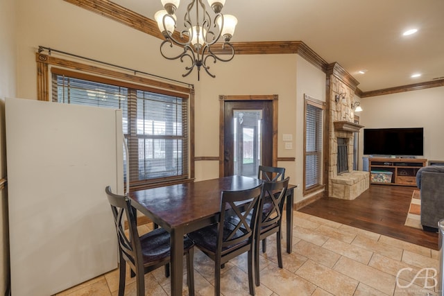 dining area featuring crown molding, a fireplace, and an inviting chandelier