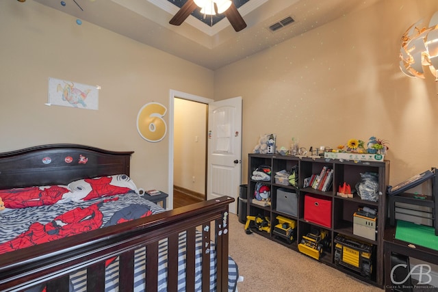 bedroom with carpet floors, ceiling fan, and a tray ceiling