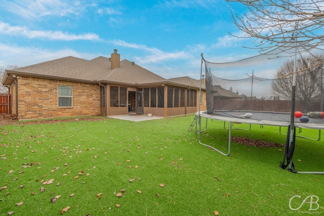 back of property featuring a sunroom, a yard, a patio area, and a trampoline