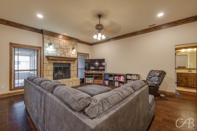 living room featuring sink, crown molding, ceiling fan, dark hardwood / wood-style floors, and a stone fireplace