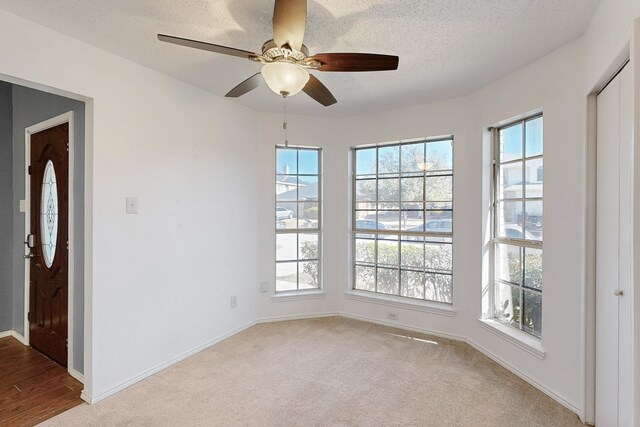 unfurnished room featuring ceiling fan, light colored carpet, and a textured ceiling