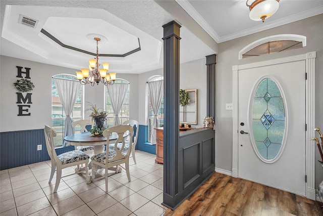 interior space with ornamental molding, plenty of natural light, a tray ceiling, and a chandelier