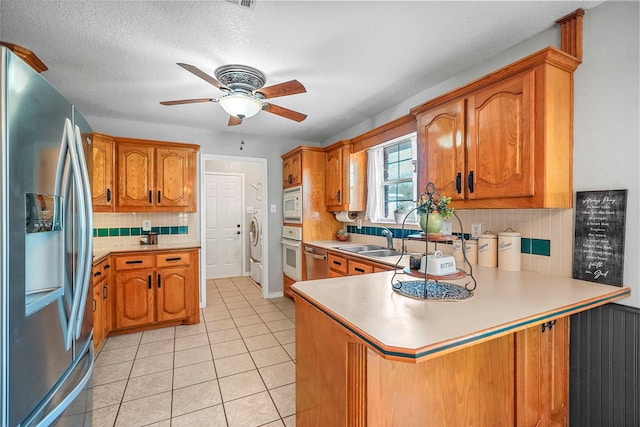 kitchen featuring light tile patterned floors, sink, ceiling fan, stainless steel appliances, and kitchen peninsula