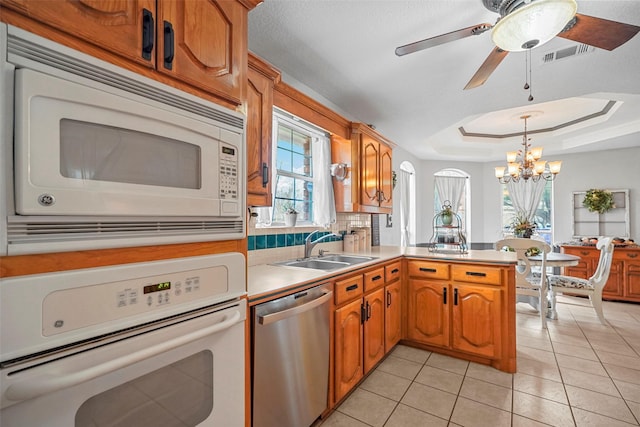 kitchen featuring light tile patterned floors, sink, white appliances, kitchen peninsula, and a raised ceiling