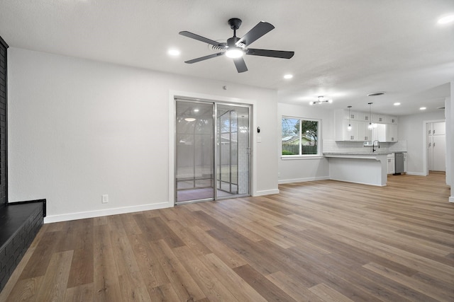 unfurnished living room featuring sink, ceiling fan, and light hardwood / wood-style flooring