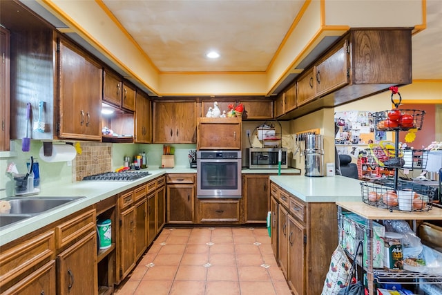 kitchen with sink, decorative backsplash, light tile patterned floors, stainless steel appliances, and crown molding