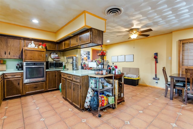 kitchen featuring stainless steel appliances, crown molding, light tile patterned floors, and ceiling fan