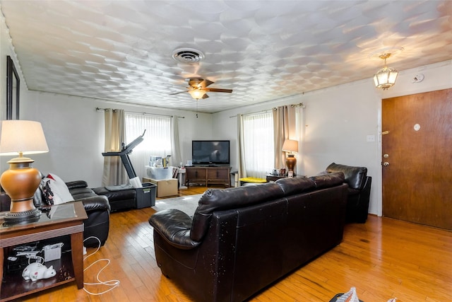 living room featuring wood-type flooring, plenty of natural light, and ceiling fan