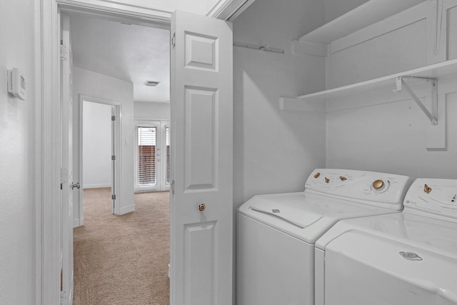 washroom with laundry area, visible vents, baseboards, light colored carpet, and washing machine and dryer