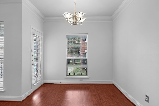 spare room featuring wood-type flooring, ornamental molding, and a chandelier