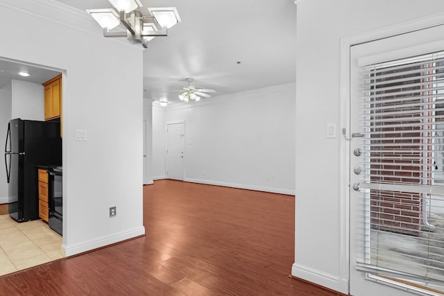 interior space featuring ornamental molding, light hardwood / wood-style floors, ceiling fan, and black appliances