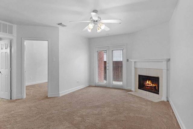 unfurnished living room featuring ceiling fan, light colored carpet, and a tiled fireplace