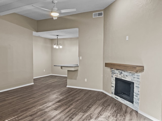 unfurnished living room featuring ceiling fan with notable chandelier, a fireplace, and dark hardwood / wood-style floors