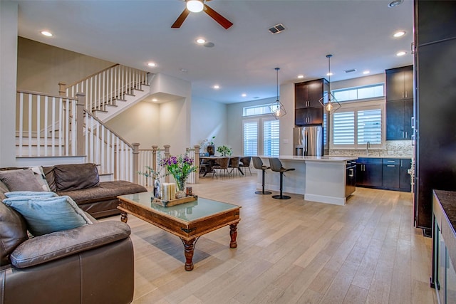 living room with ceiling fan, sink, and light hardwood / wood-style flooring