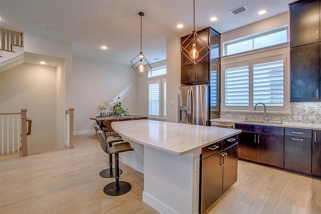 kitchen featuring dark brown cabinetry, stainless steel fridge, a center island, and sink