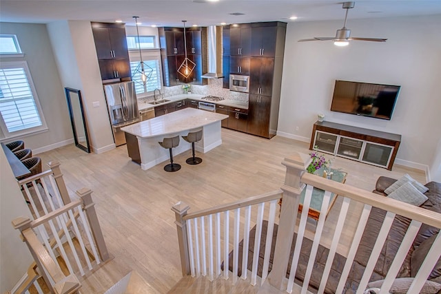 living room featuring sink, ceiling fan, and light wood-type flooring