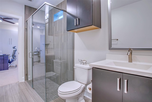 bathroom with ceiling fan, vanity, toilet, and an enclosed shower