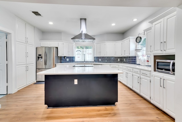 kitchen with appliances with stainless steel finishes, a center island, island range hood, and white cabinets