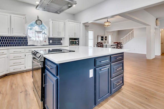 kitchen with range with electric stovetop, pendant lighting, blue cabinets, white cabinets, and wall chimney range hood