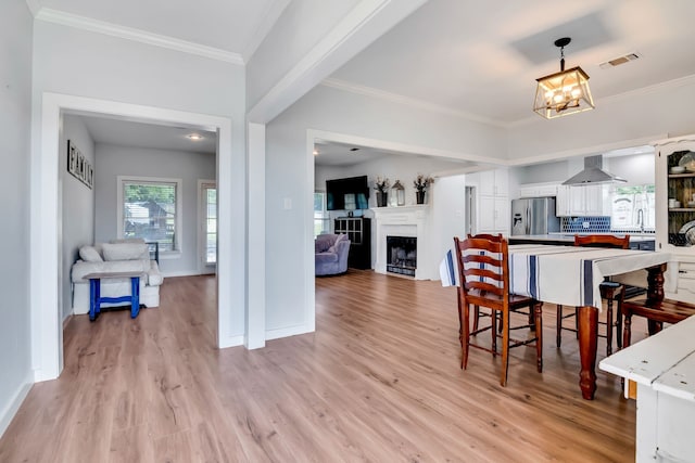 dining space featuring an inviting chandelier, ornamental molding, and light wood-type flooring