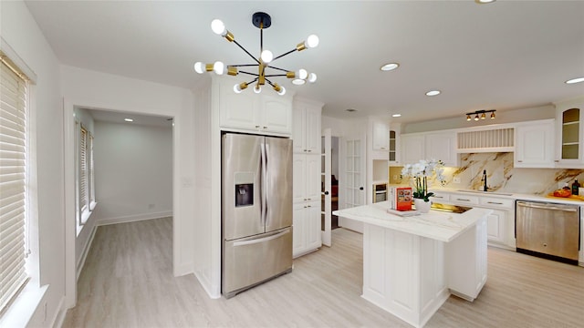 kitchen with sink, white cabinetry, pendant lighting, stainless steel appliances, and light hardwood / wood-style floors