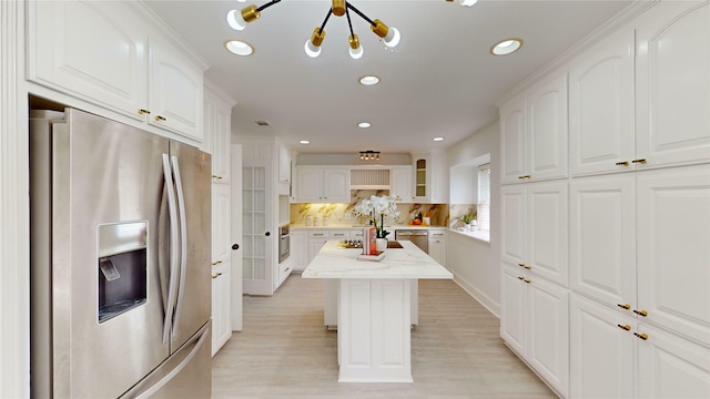 kitchen with white cabinetry, backsplash, stainless steel appliances, light stone countertops, and a kitchen island