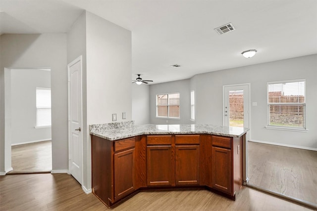 kitchen featuring light stone counters, light wood-type flooring, and a wealth of natural light