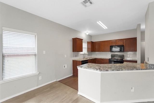 kitchen with sink, light stone counters, tasteful backsplash, light hardwood / wood-style floors, and black appliances