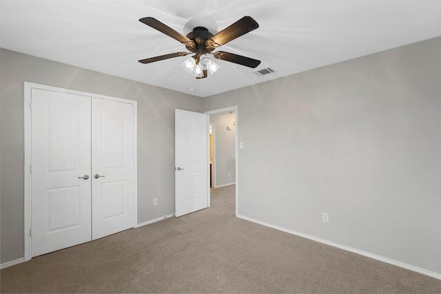 unfurnished bedroom featuring ceiling fan, light colored carpet, and a closet