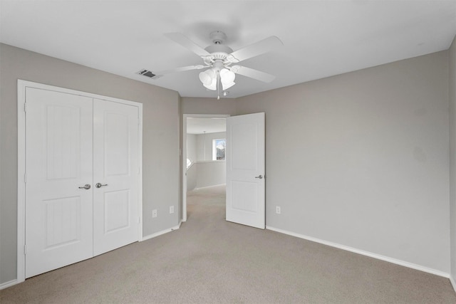 unfurnished bedroom with ceiling fan, a closet, and light carpet