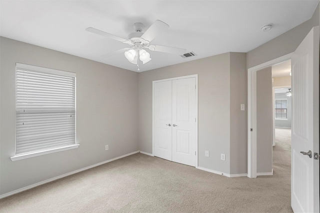 unfurnished bedroom with light carpet, a closet, and ceiling fan