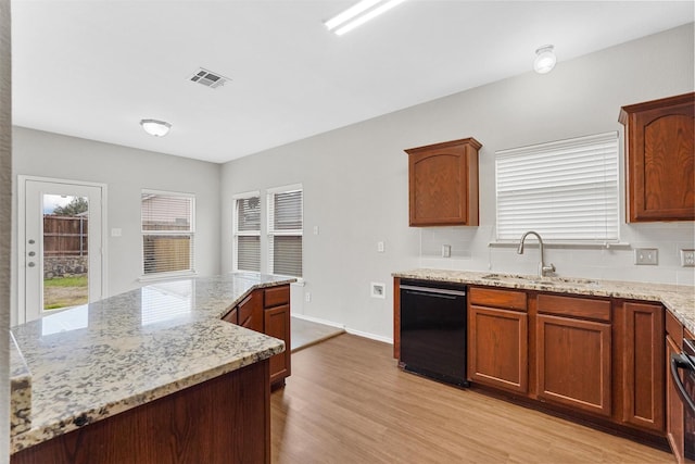 kitchen featuring sink, black dishwasher, light stone counters, light hardwood / wood-style floors, and decorative backsplash