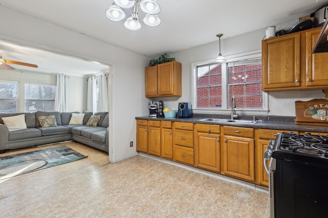 kitchen with ceiling fan, sink, hanging light fixtures, and stainless steel gas range oven