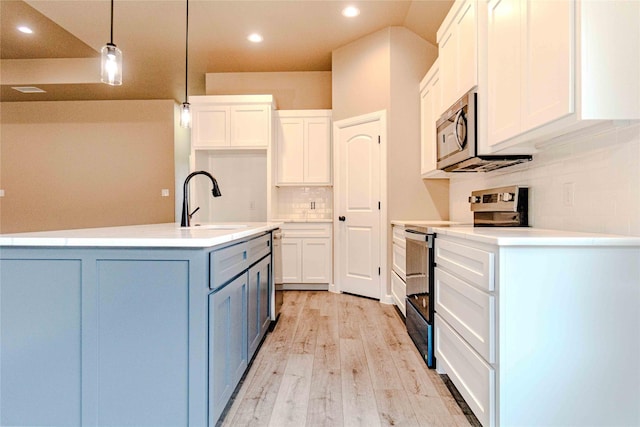 kitchen featuring pendant lighting, stainless steel appliances, a kitchen island with sink, and white cabinets