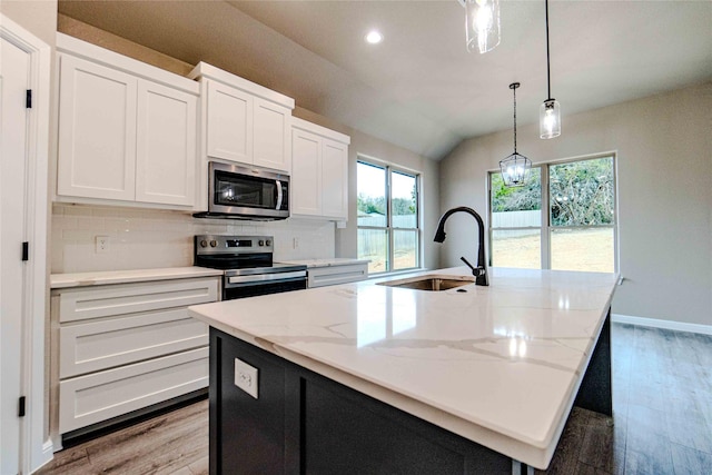 kitchen with stainless steel appliances, an island with sink, sink, and white cabinets