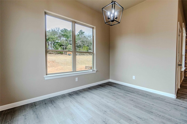 unfurnished dining area featuring a chandelier and light wood-type flooring