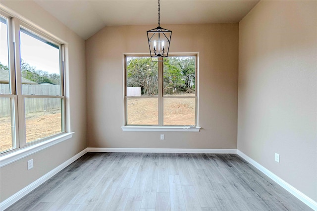 unfurnished dining area with plenty of natural light, a chandelier, and light wood-type flooring