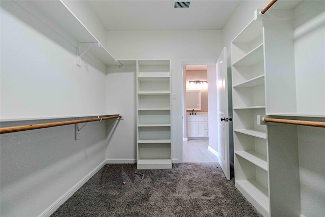 walk in closet featuring sink and dark colored carpet