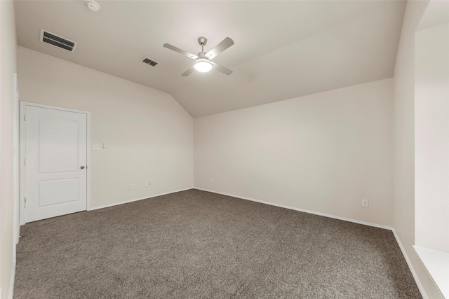 empty room featuring ceiling fan, vaulted ceiling, and dark colored carpet