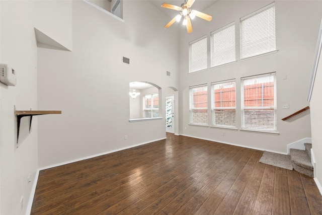 unfurnished living room with dark hardwood / wood-style flooring, ceiling fan, and a high ceiling