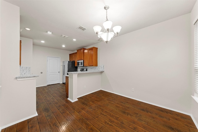 kitchen with tasteful backsplash, a chandelier, kitchen peninsula, stainless steel appliances, and dark wood-type flooring