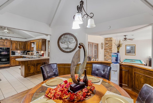 dining area featuring ceiling fan, sink, lofted ceiling with beams, and light tile patterned floors