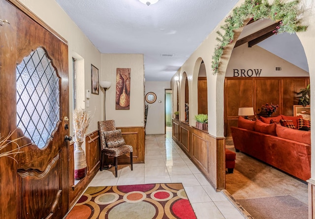 tiled foyer with beam ceiling and a textured ceiling